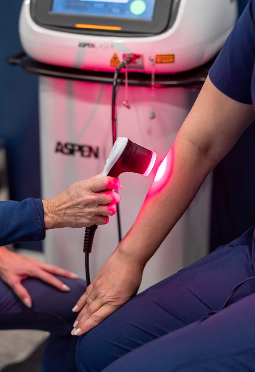 Chiropractor applying Aspen Laser Therapy on a patient’s arm