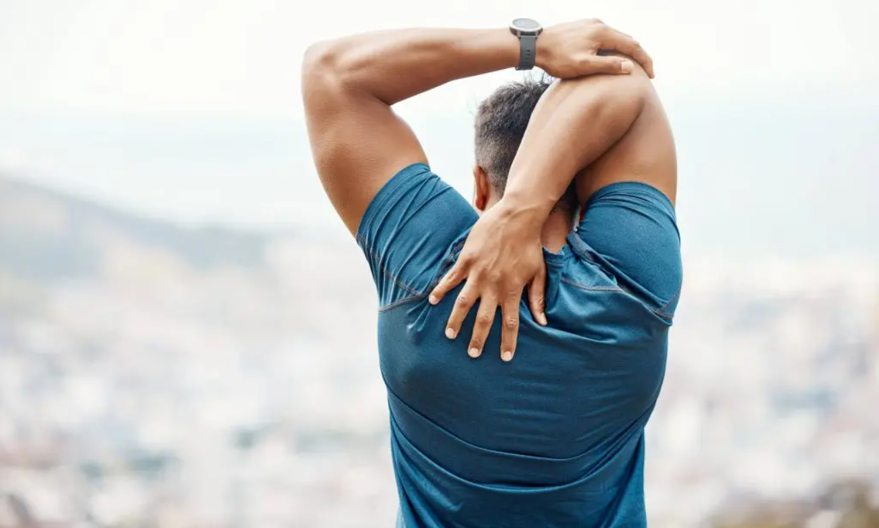 Man stretching his shoulder outdoors for better flexibility and wellness